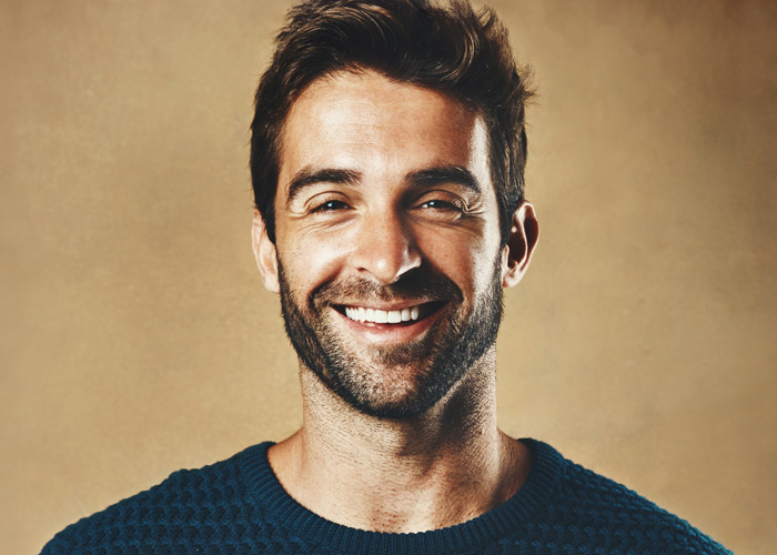 closeup of man smiling on gold background